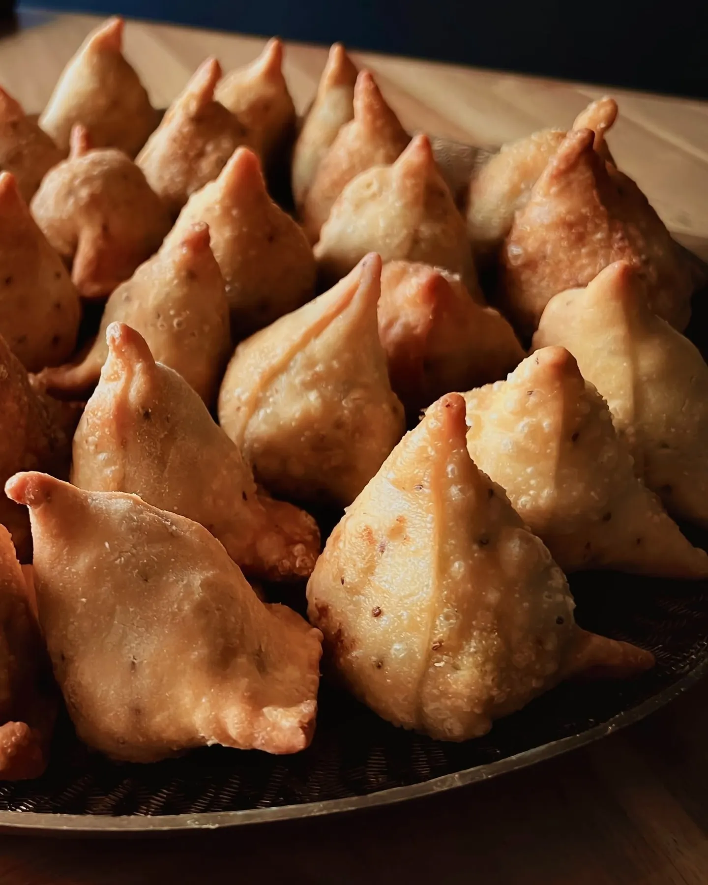 Handmade samosas piled on a platter