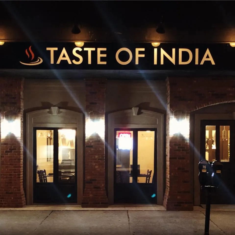 The Taste of India storefront at night, gold lettering over brick arches on Kent Street